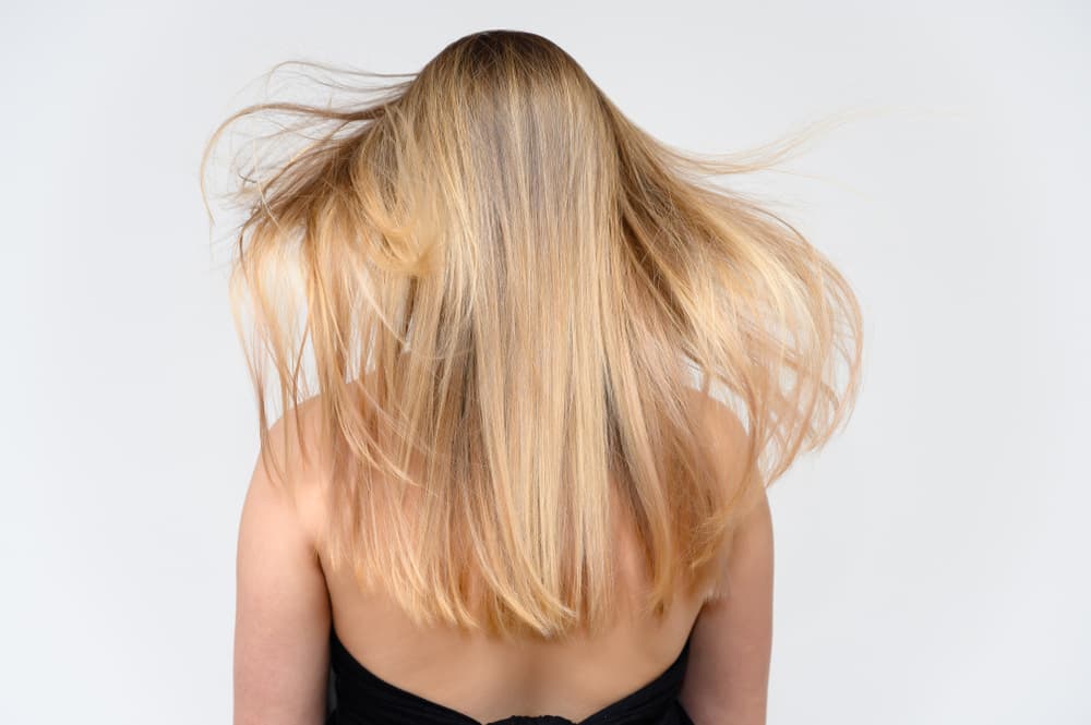 Long straight blonde hair styled with full head highlights