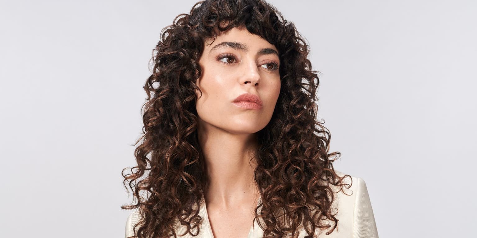 Woman with defined dark curls styled after professional full head perm