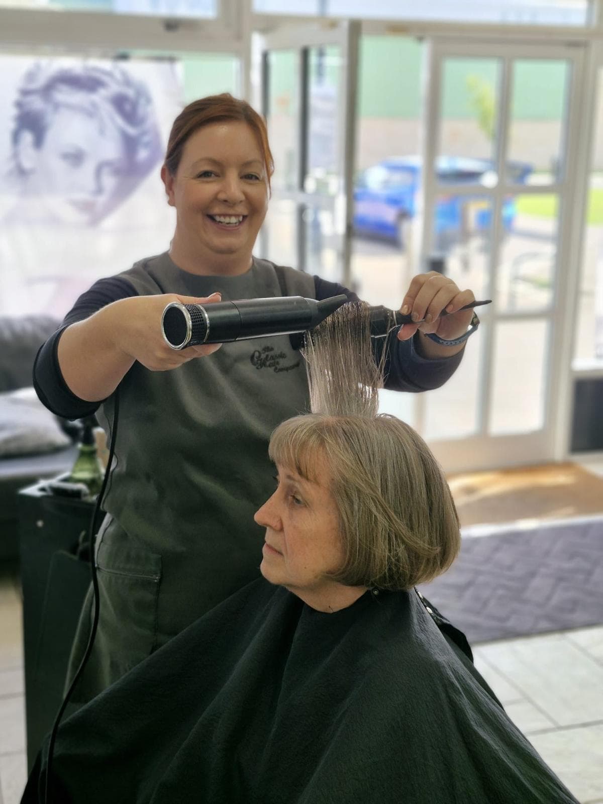 Nicole Burgess, Advanced Stylist at The Classic Hair Company in Tilbury, Essex, styling a client’s hair with a round brush and dryer in the salon.
