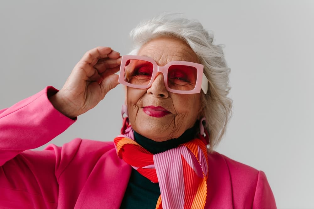 Stylish older woman with silver hair and bright fashion accessories, representing professional OAP hairdressing services at The Classic Hair Company in Tilbury.