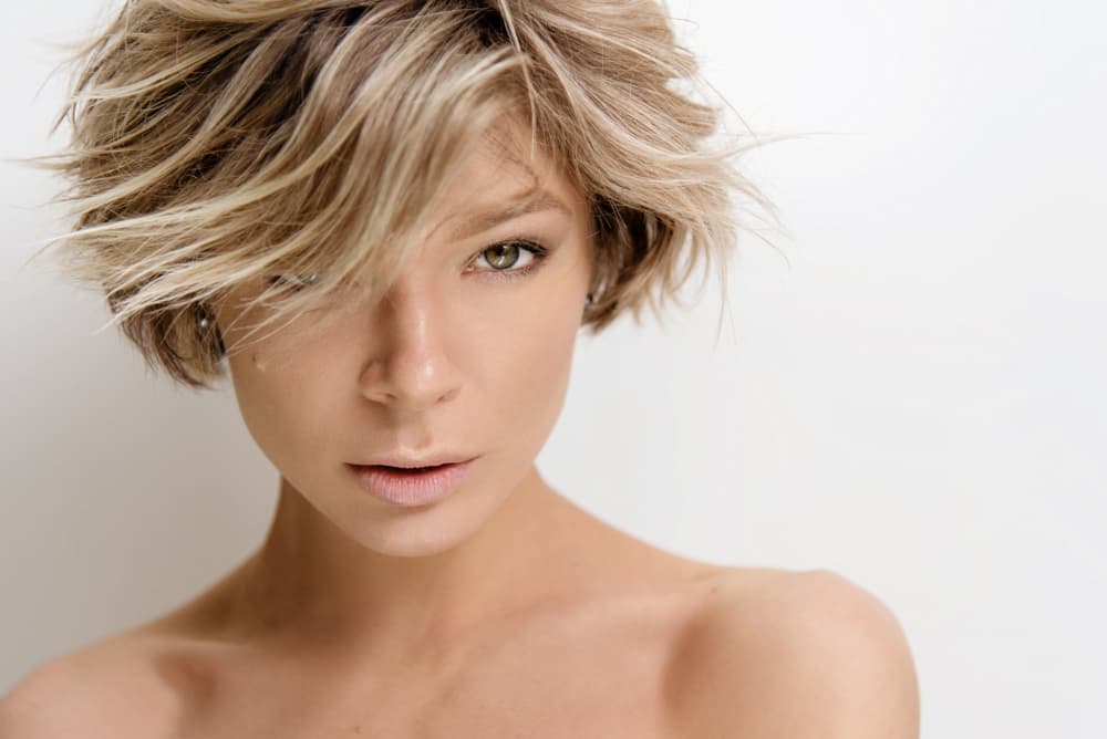 Woman with short layered blonde hair featuring parting highlights