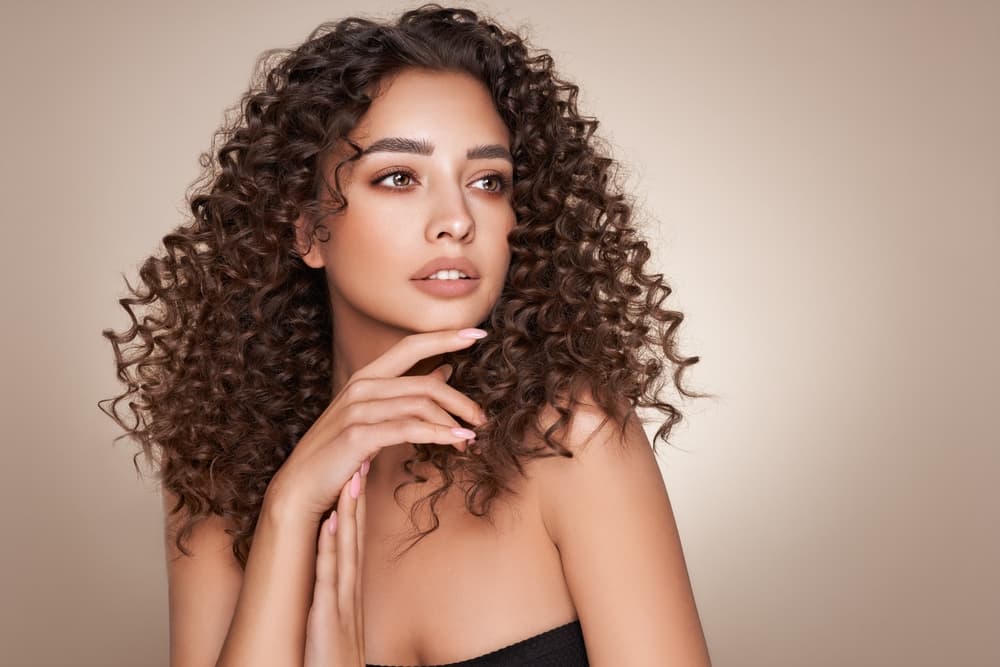 Beautiful woman with defined, glossy curls created through professional perming at The Classic Hair Company in Tilbury.