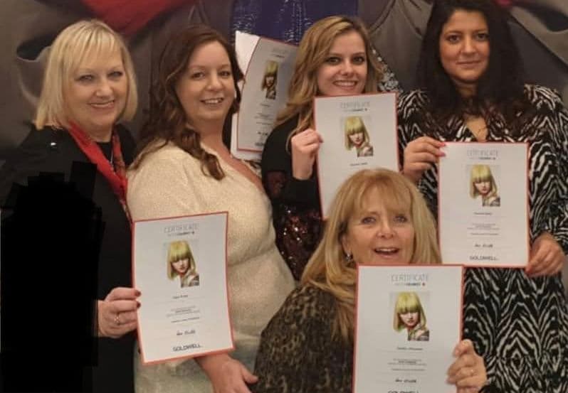 The Classic Hair Company team proudly holding certificates after completing professional hairdressing training.